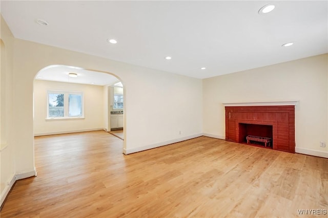 unfurnished living room featuring a brick fireplace and light hardwood / wood-style flooring