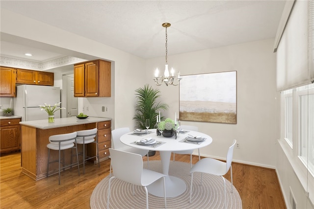 dining space with a notable chandelier and light hardwood / wood-style floors