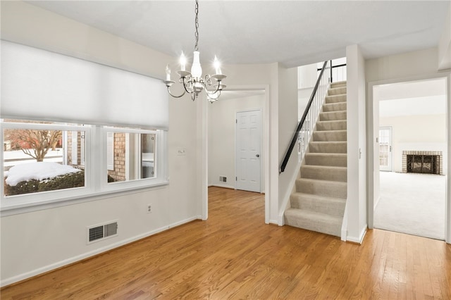 interior space featuring a fireplace, a notable chandelier, and light hardwood / wood-style flooring