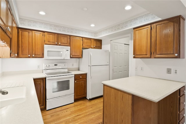 kitchen with white appliances, kitchen peninsula, light hardwood / wood-style flooring, and sink