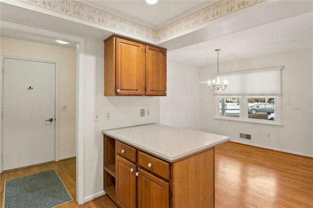 kitchen featuring hanging light fixtures, light hardwood / wood-style flooring, an inviting chandelier, and kitchen peninsula