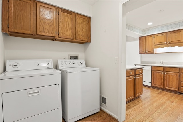 clothes washing area featuring washing machine and clothes dryer, light hardwood / wood-style floors, and sink