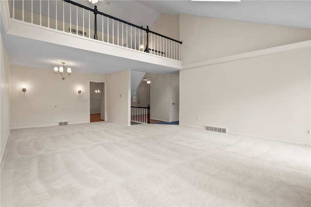 unfurnished living room featuring a notable chandelier, high vaulted ceiling, and carpet floors