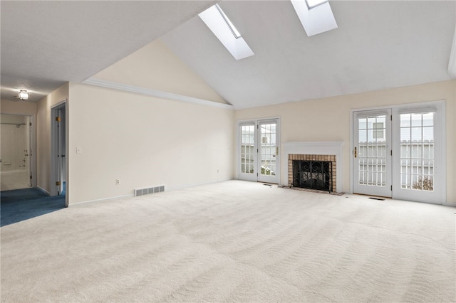 unfurnished living room with high vaulted ceiling, a brick fireplace, a skylight, and carpet flooring