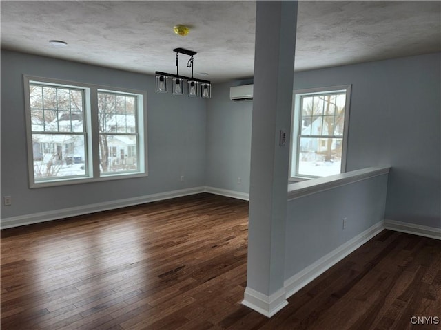 unfurnished dining area with dark wood-type flooring, an AC wall unit, and a textured ceiling