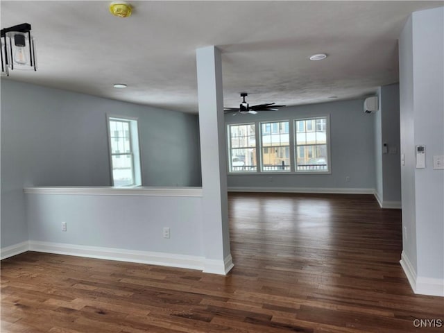 empty room with ceiling fan, a wall unit AC, dark hardwood / wood-style floors, and plenty of natural light