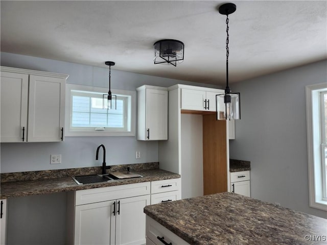 kitchen featuring sink, hanging light fixtures, and white cabinetry