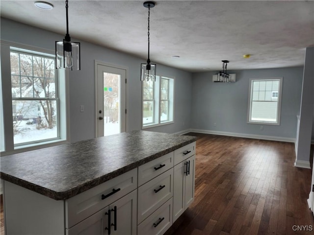 kitchen with a healthy amount of sunlight, hanging light fixtures, white cabinetry, and a center island