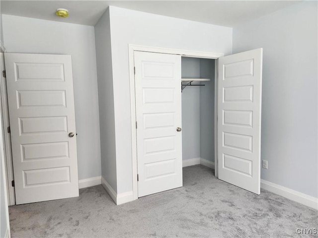 unfurnished bedroom featuring a closet and light carpet