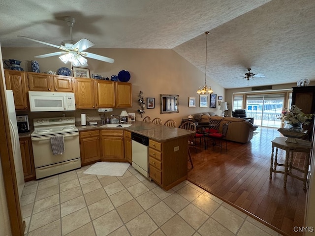 kitchen featuring vaulted ceiling, white appliances, light tile patterned floors, kitchen peninsula, and ceiling fan with notable chandelier