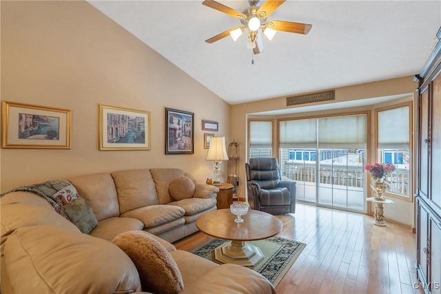 living room with light hardwood / wood-style floors, ceiling fan, and vaulted ceiling