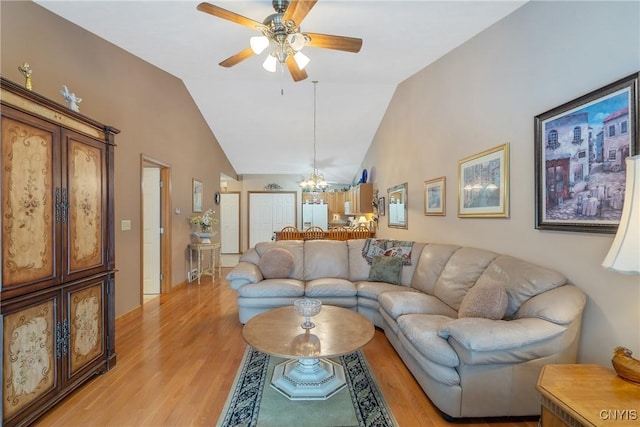 living room with vaulted ceiling, ceiling fan with notable chandelier, and light hardwood / wood-style floors