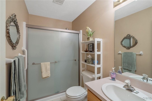 bathroom featuring toilet, a textured ceiling, a shower with shower door, and vanity