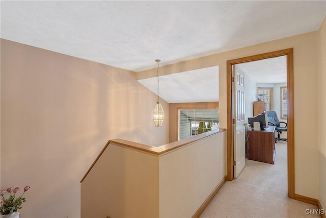 hallway featuring light colored carpet, a chandelier, and a textured ceiling