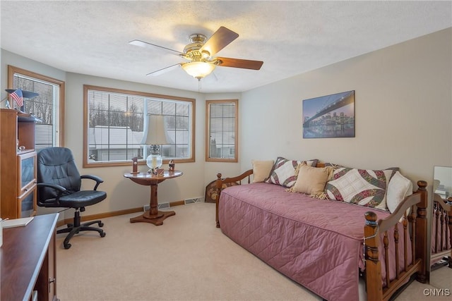 bedroom featuring ceiling fan, light carpet, and a textured ceiling