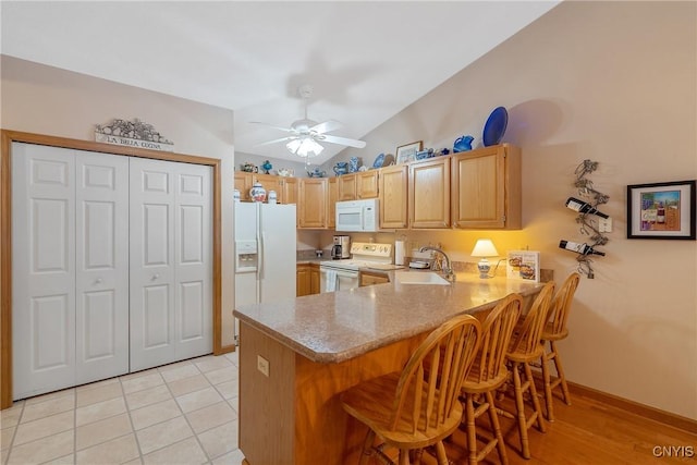 kitchen with white appliances, a kitchen bar, sink, kitchen peninsula, and light tile patterned floors