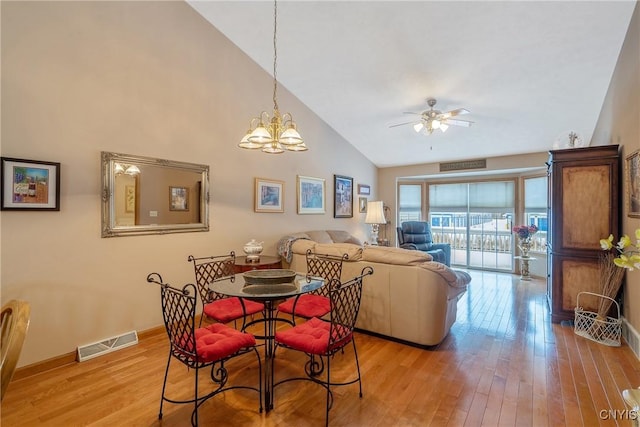 dining area with vaulted ceiling, ceiling fan with notable chandelier, and light hardwood / wood-style floors