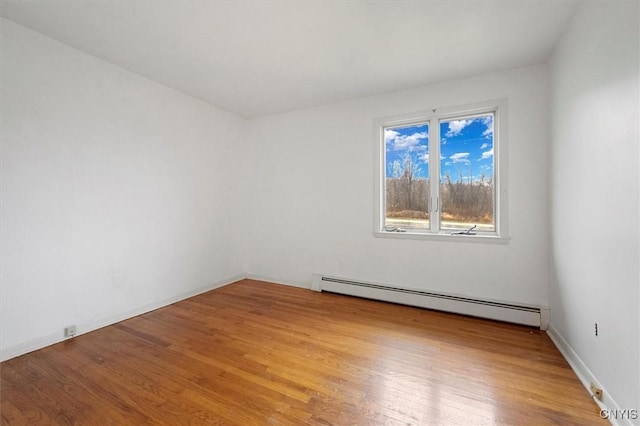 unfurnished room with a baseboard heating unit and light hardwood / wood-style floors