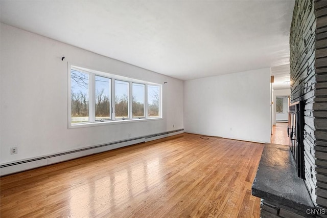 unfurnished living room with light hardwood / wood-style floors, a stone fireplace, and a baseboard radiator