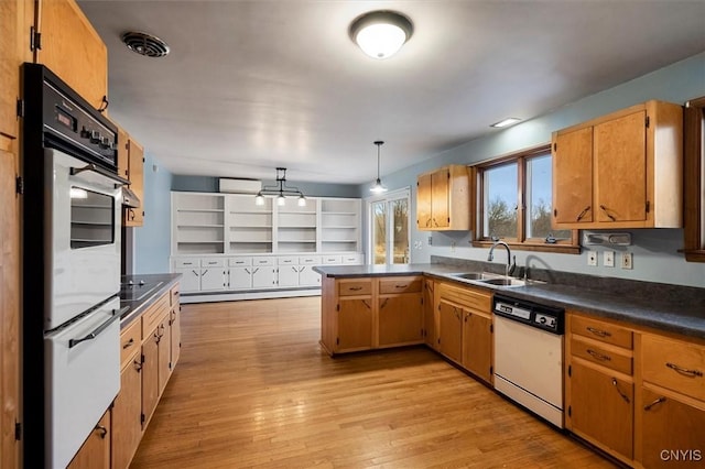 kitchen featuring white appliances, kitchen peninsula, decorative light fixtures, light wood-type flooring, and sink