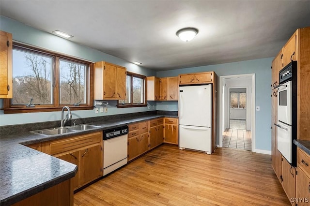 kitchen with white appliances, light wood-type flooring, and sink