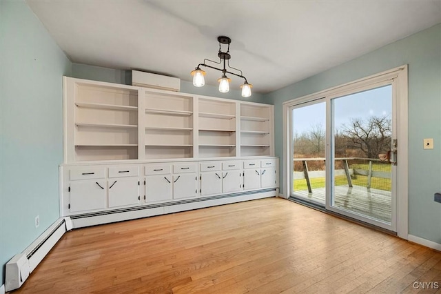 unfurnished living room featuring light wood-type flooring, a wall unit AC, a baseboard radiator, and a chandelier