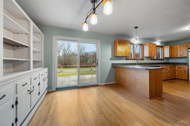 kitchen featuring sink, white cabinetry, light wood-type flooring, kitchen peninsula, and hanging light fixtures