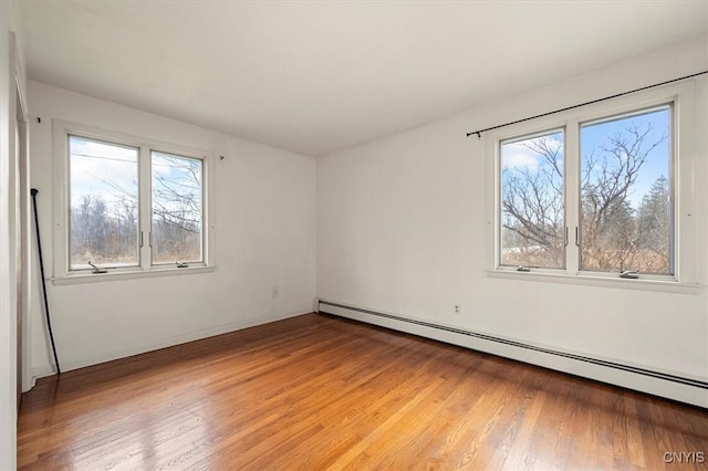 empty room featuring baseboard heating and hardwood / wood-style flooring