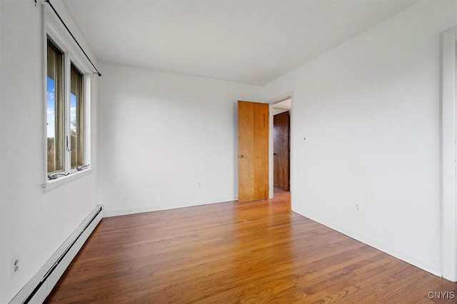 unfurnished room with wood-type flooring and a baseboard heating unit