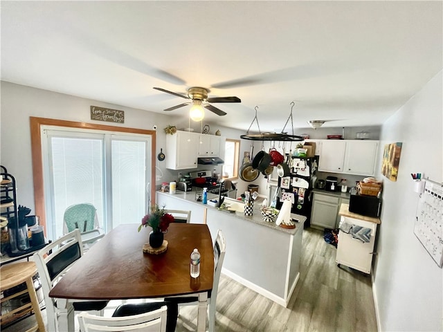 kitchen featuring black refrigerator, white cabinetry, hardwood / wood-style floors, and kitchen peninsula