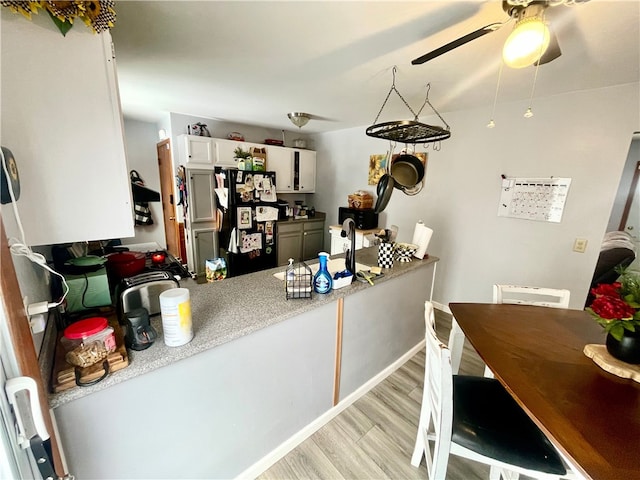 kitchen featuring white cabinets, light hardwood / wood-style flooring, and black refrigerator