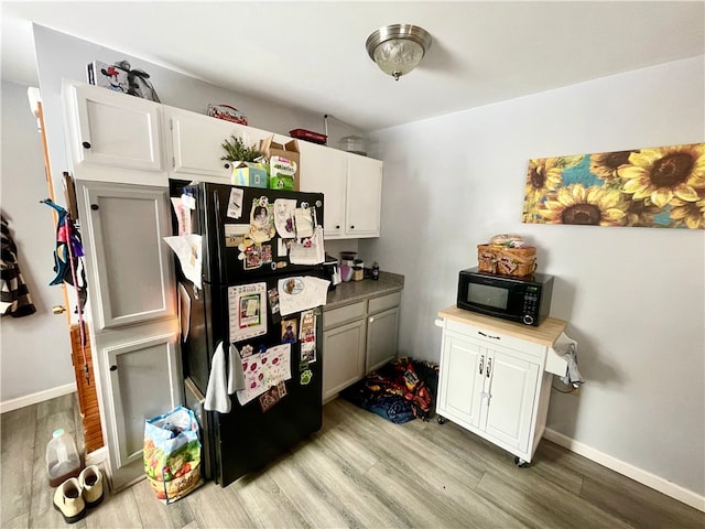 kitchen featuring light hardwood / wood-style flooring, black appliances, and white cabinetry