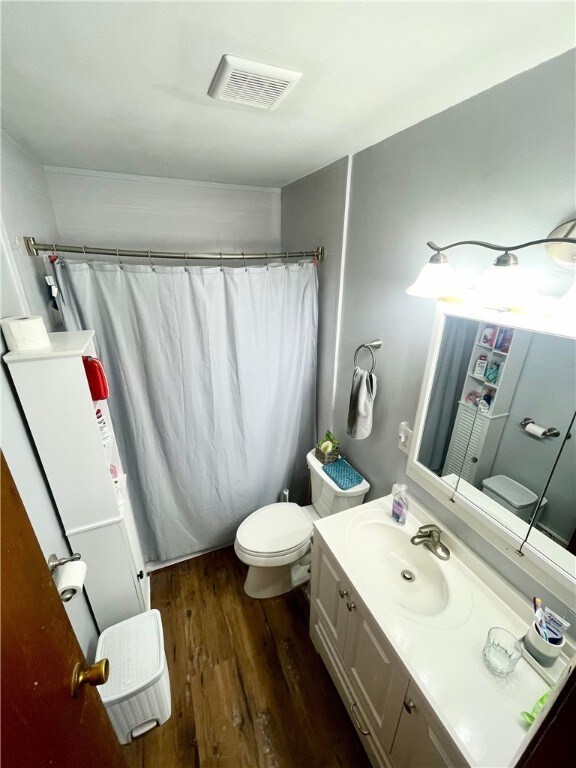 bathroom featuring curtained shower, toilet, vanity, and wood-type flooring