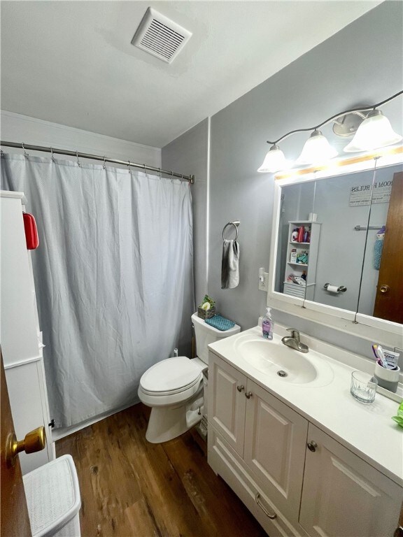 bathroom with curtained shower, toilet, vanity, and wood-type flooring