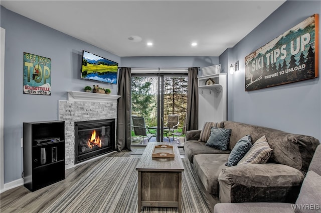 living room featuring light wood-type flooring and a stone fireplace