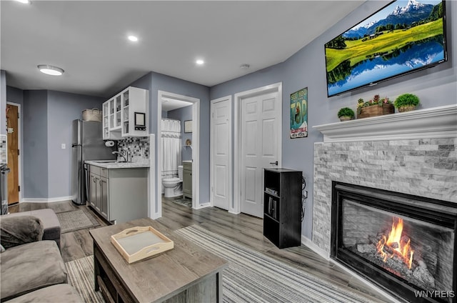 living room with a fireplace, light wood-type flooring, and sink