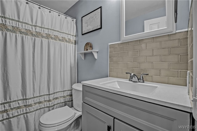 bathroom featuring toilet, vanity, and decorative backsplash