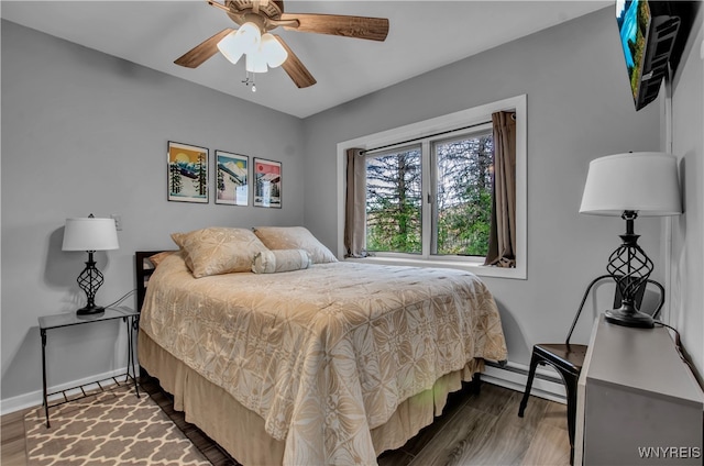 bedroom with baseboard heating, ceiling fan, and dark hardwood / wood-style floors