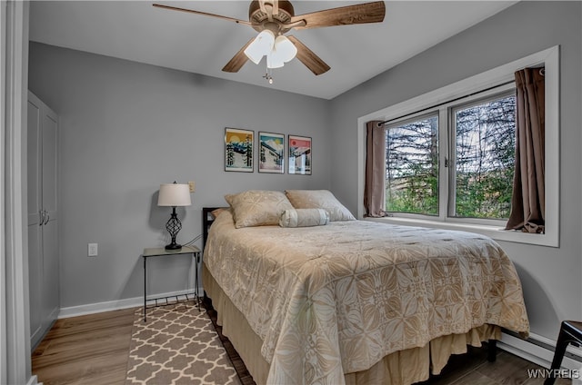 bedroom with a baseboard radiator, ceiling fan, and hardwood / wood-style flooring