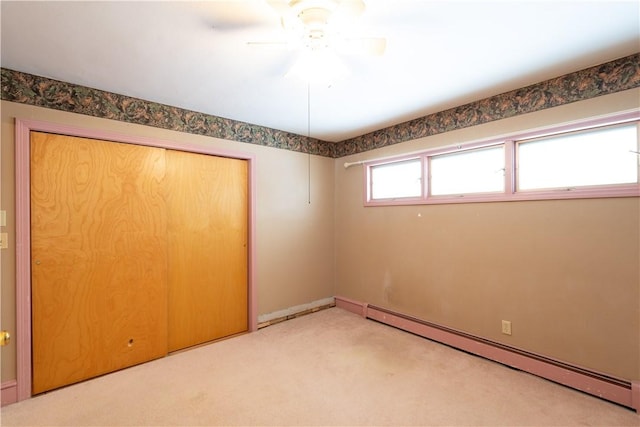 unfurnished bedroom with ceiling fan, a baseboard radiator, a closet, and carpet