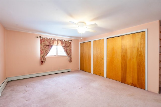 unfurnished bedroom featuring ceiling fan, baseboard heating, two closets, and carpet