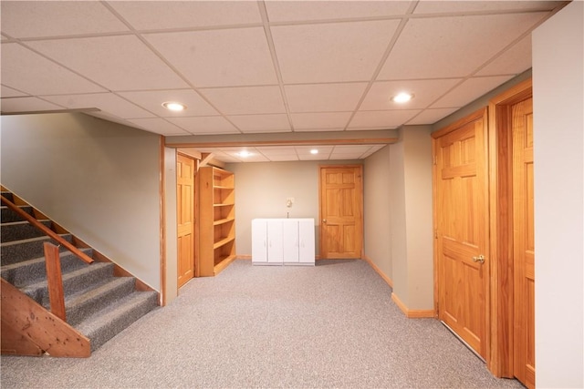 basement with light colored carpet and a drop ceiling