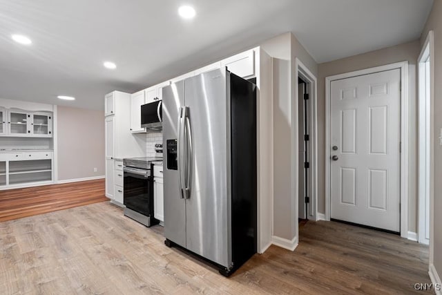 kitchen featuring appliances with stainless steel finishes, light hardwood / wood-style flooring, white cabinetry, and decorative backsplash