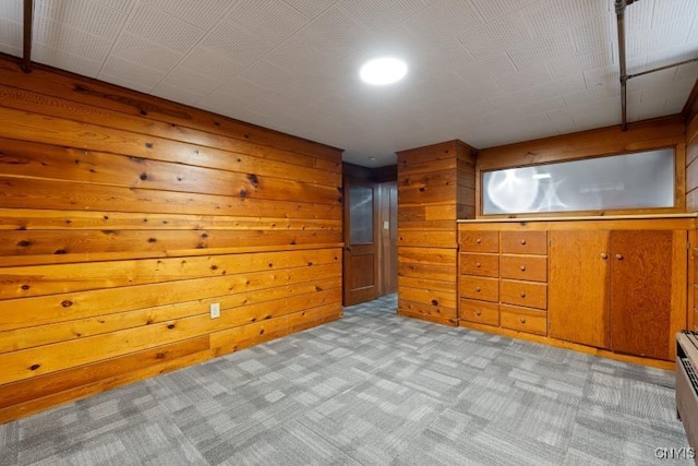 bonus room featuring light carpet and wood walls