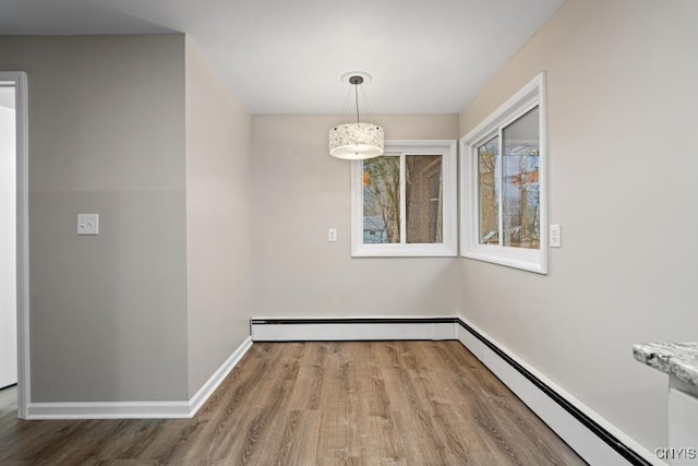 unfurnished dining area featuring hardwood / wood-style floors and a baseboard radiator