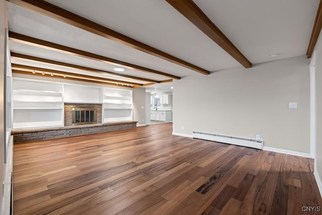 unfurnished living room featuring a fireplace, beamed ceiling, hardwood / wood-style floors, baseboard heating, and built in shelves