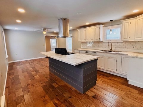 kitchen with island range hood, tasteful backsplash, a kitchen island, white cabinets, and sink