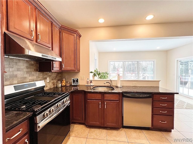 kitchen featuring stainless steel appliances, dark stone counters, light tile patterned floors, and sink