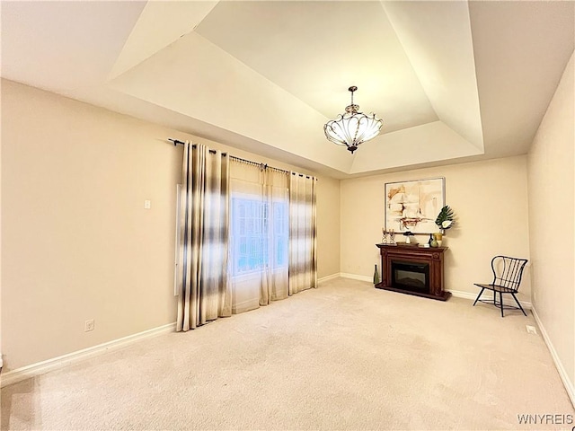 sitting room with an inviting chandelier, carpet flooring, and a tray ceiling