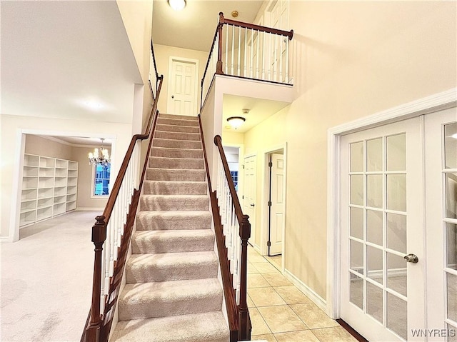 staircase with french doors, carpet, and a chandelier